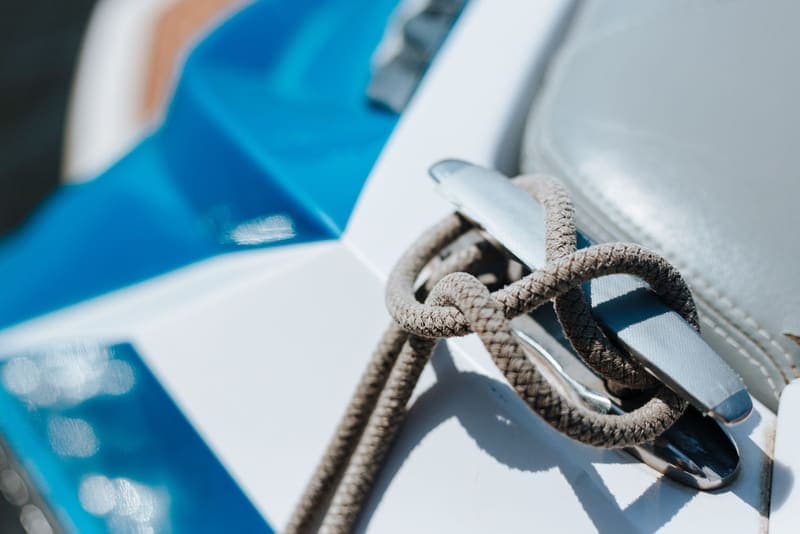 A rope tied off on a metal cleat on the deck of a boat