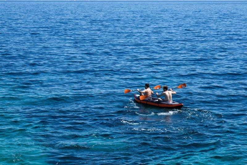 Two paddlers on open water in bright sunlight