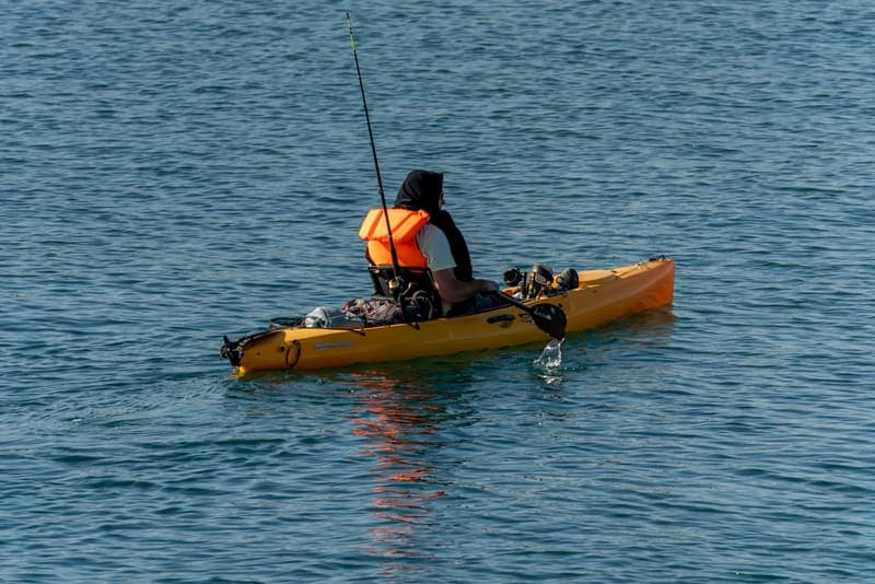 A solo angler fishing from a kayak on calm water
