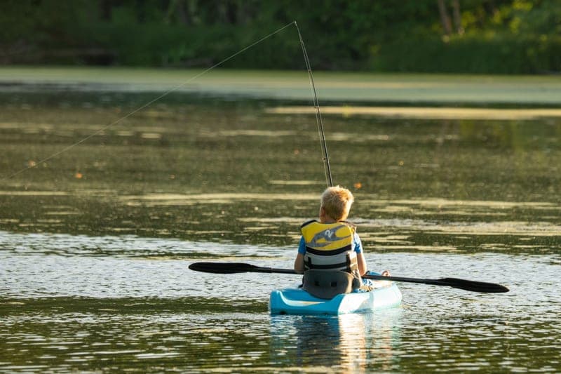A fishing kayak rigged with gear on calm water
