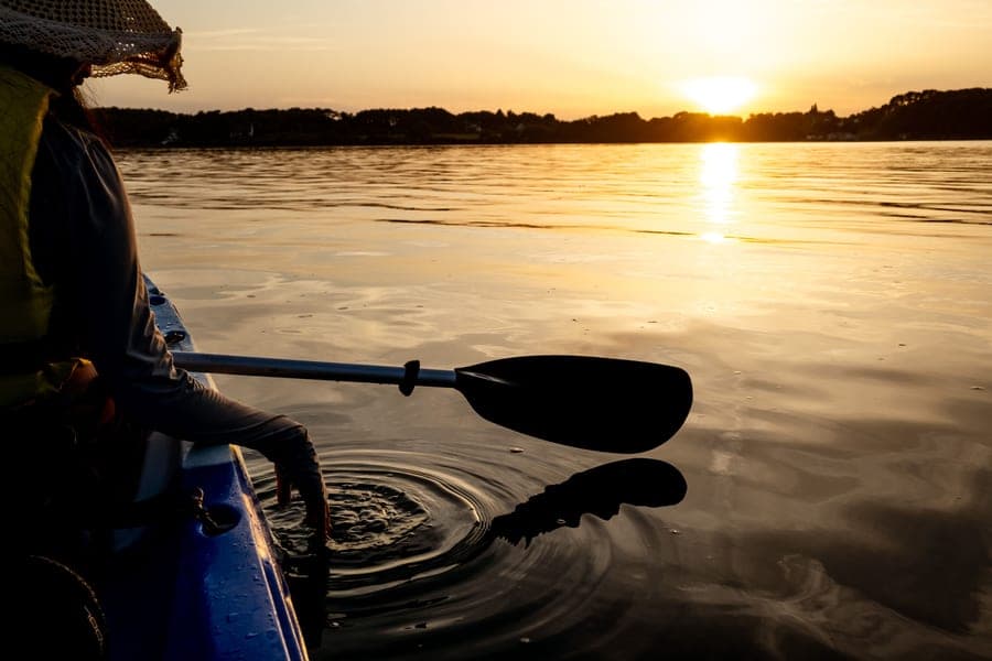 A kayak paddle held above the surface of a lake