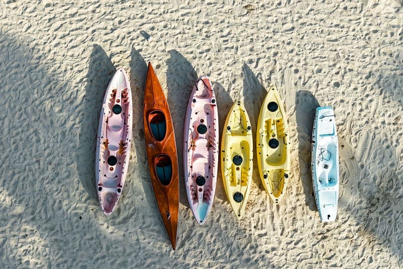Brightly colored kayaks resting on a sunlit sandy beach