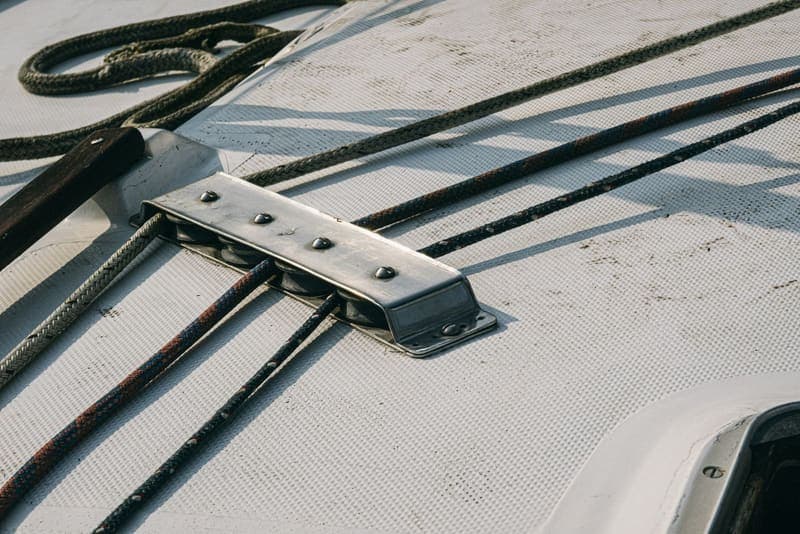 Lines running under a bolted deck fitting on the deck of a boat