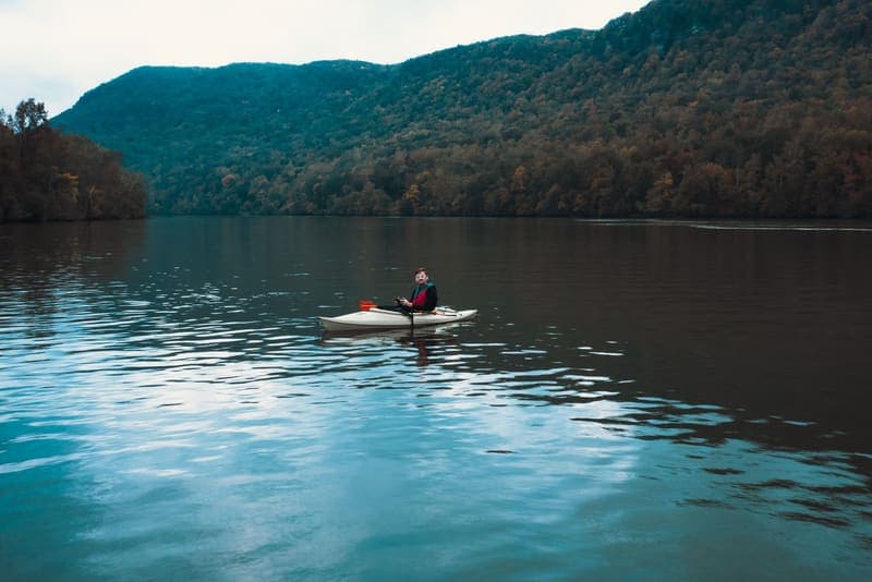 A paddler seated in a kayak on a calm lake
