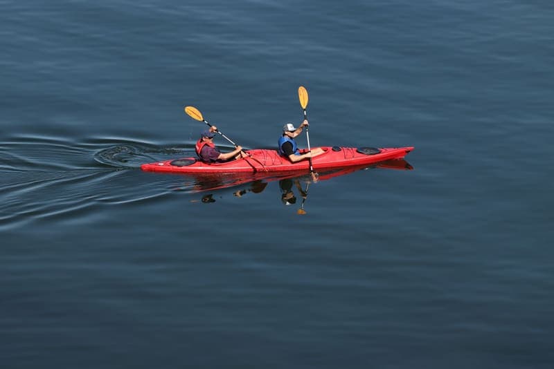 A two-person tandem kayak on a calm lake