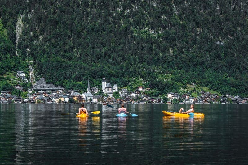 Three kayakers paddling together on a calm alpine lake