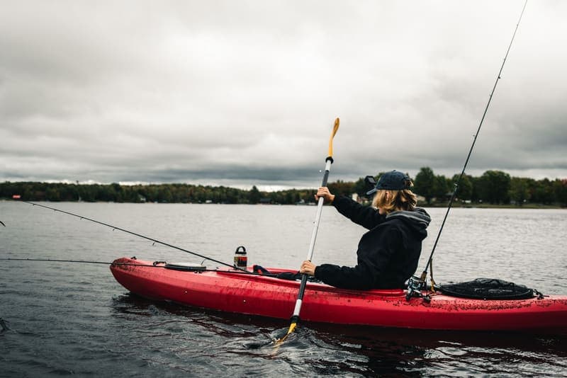 A person paddling and fishing from a kayak on a calm lake
