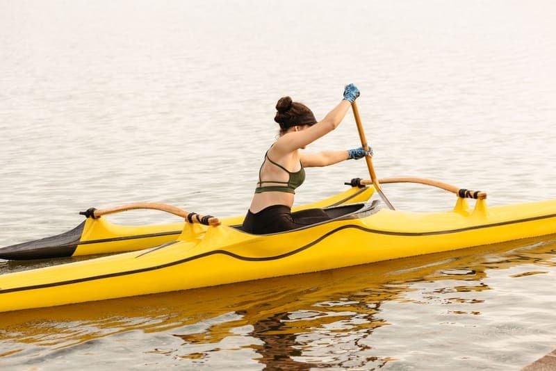 A paddler using a kayak paddle on a calm lake