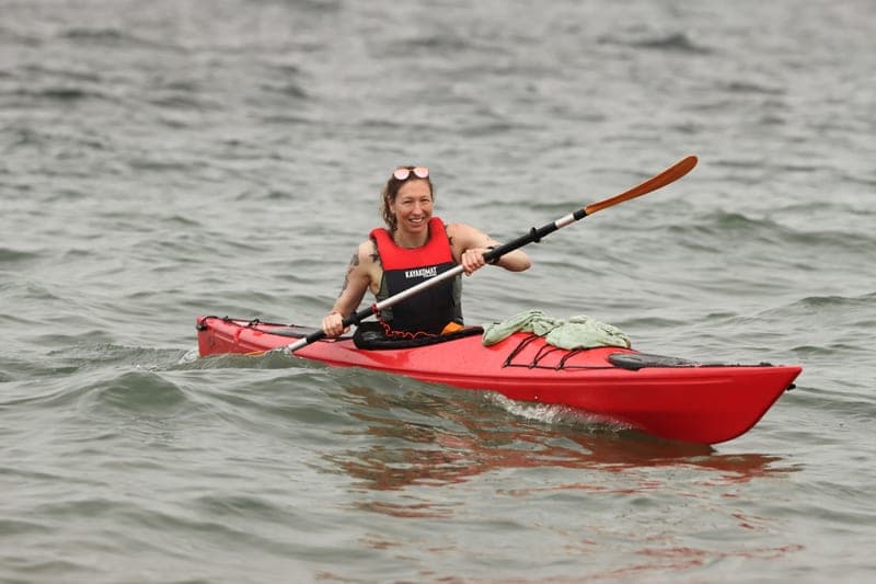 A paddler wearing a life jacket in a kayak on calm water