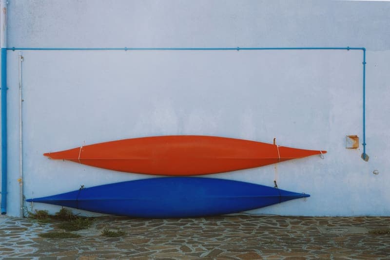 A red and a blue kayak stored horizontally against a wall