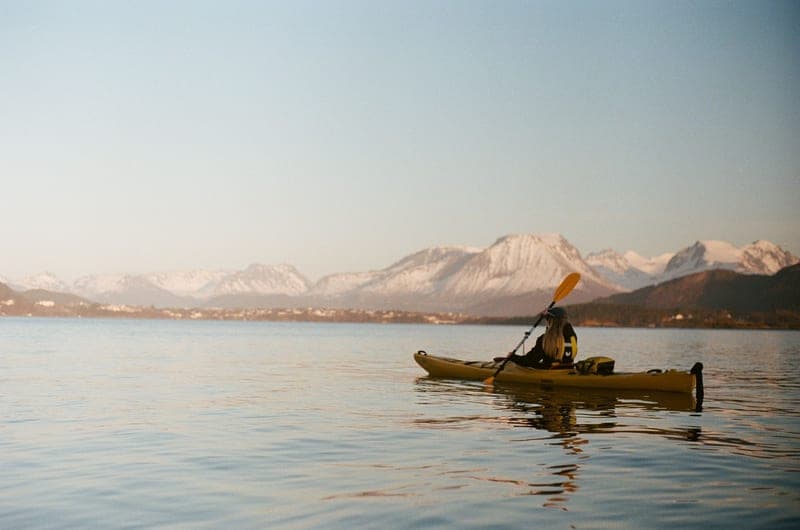 A person loading a kayak onto a car