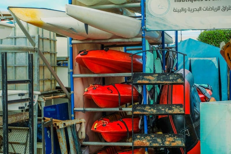 Kayaks stacked and strapped on a multi-tier outdoor storage rack