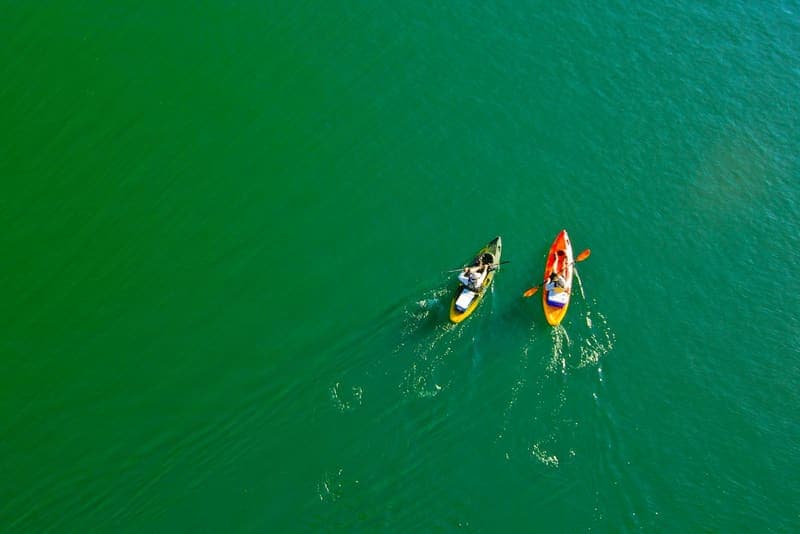 Two colorful kayaks being paddled across a lake