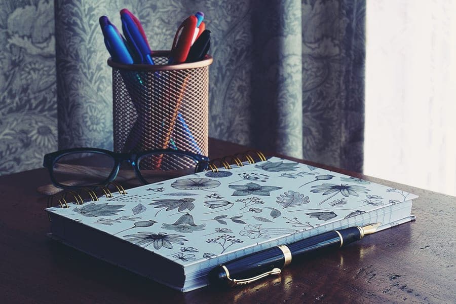 A notebook and pen on a wooden desk